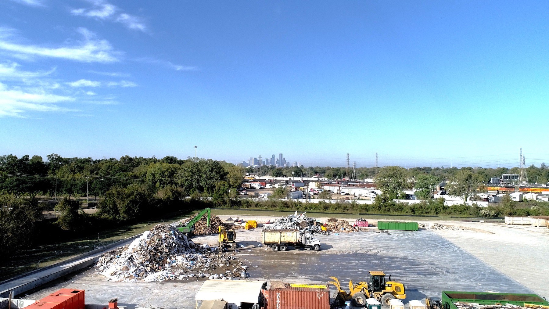 Trucks working at the Houston dump with the Houston skyline in the background.