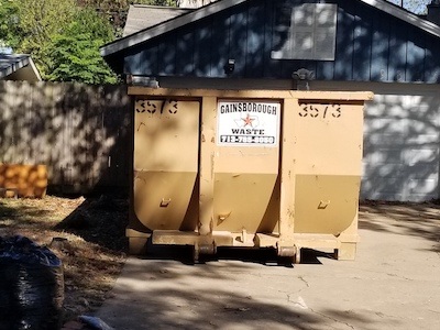 A yard waste dumpster outside a residential home for a cleanup.