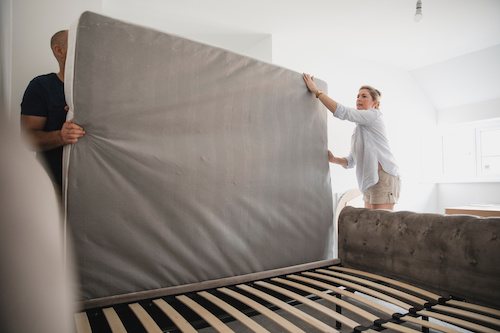 A couple preparing to throw away their old mattress wondering can you put a mattress in a dumpster?