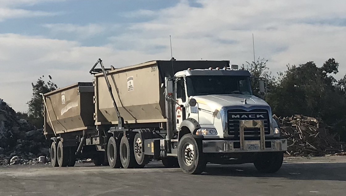A heavy debris dumpster is being driven to a new location.
