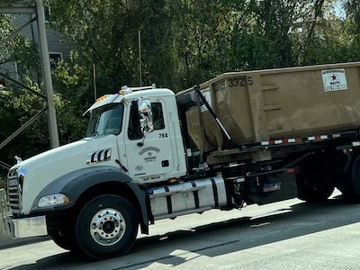 The Reliable Waste Solution 22 Gainsborough Waste roll-off dumpster being transported on the back of a truck