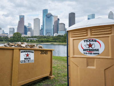 Gainsborough Waste roll-off dumpster next to a Texas Outhouse portable toilet at a job site in Houston, TX